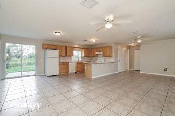 Lehigh Acres house for rent - a large kitchen with white appliances and wooden cabinets and tiled floors