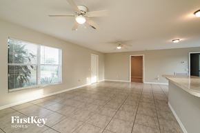 Lehigh Acres house for rent - an empty living room with a ceiling fan and a large window