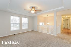 Kearney house for rent - A spacious room with a carpeted floor, a ceiling fan, and a staircase.