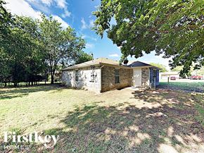 Grand Prairie house for rent - a small stone house with a yard and trees
