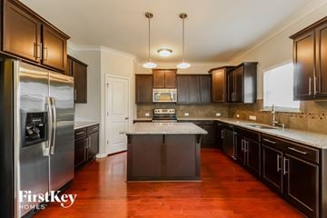 Winston-Salem house for rent - A kitchen with dark wood cabinets and a stainless steel refrigerator.