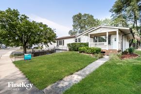 Carpentersville house for rent - A white house with a porch and a tree in front of it.