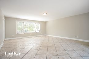 Carpentersville house for rent - A spacious room with tiled flooring and a window with blinds.