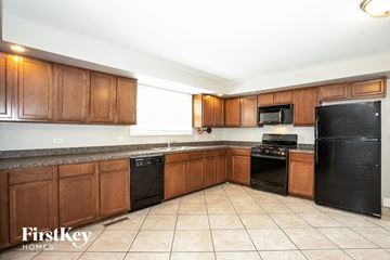 Carpentersville house for rent - A kitchen with black appliances and brown cabinets.