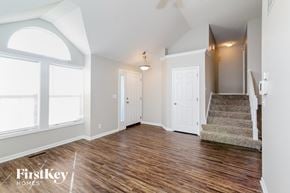 Belton house for rent - A spacious room with wood flooring and a staircase leading to another room.