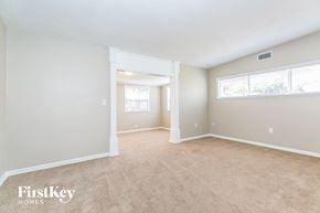 Cocoa house for rent - A spacious room with beige carpeting and white walls, with a window on the right wall.