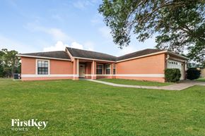 Kissimmee house for rent - a brick house with a grass lawn and a tree