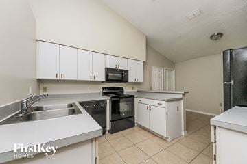 Kissimmee house for rent - a kitchen with white cabinets and black appliances and a sink