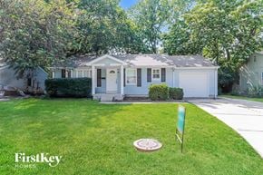 Olathe house for rent - a small white house with a yard and a sprinkler on the grass
