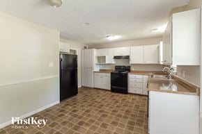 Olathe house for rent - a white kitchen with black appliances and white cabinets