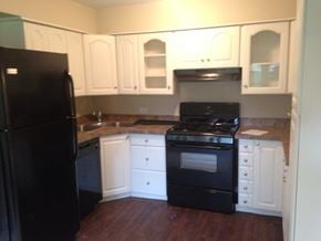 Matteson house for rent - an empty kitchen with black appliances and white cabinets