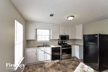 College Park house for rent - a kitchen with white cabinets and black appliances