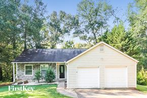 Woodstock house for rent - A house with a garage is surrounded by trees.