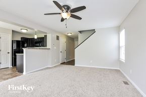 Wentzville house for rent - A spacious room with a ceiling fan and a staircase.