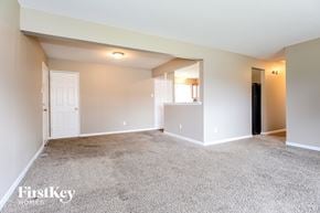 Florissant house for rent - an empty living room with carpet and a door to a kitchen