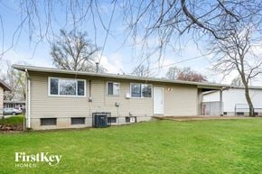 Florissant house for rent - a yellow house with a green lawn and some trees