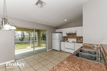 Cape Coral house for rent - a kitchen with white appliances and a sink and a window
