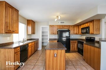 Chandler house for rent - A kitchen with wooden cabinets and black appliances.
