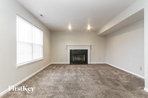 Indianapolis house for rent - A spacious living room with a fireplace and carpeted floor.