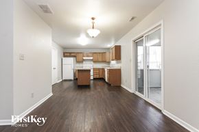 Indianapolis house for rent - A room with wooden floors and a kitchen area with white appliances.