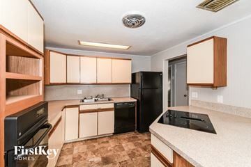 Jacksonville house for rent - a kitchen with white cabinets and black appliances