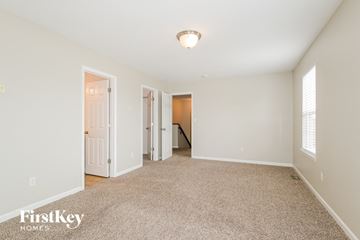 O'fallon house for rent - a spacious living room with carpet and a door to a hallway