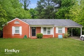 Forest Park house for rent - a small brick house with a yard and a chair in front of it