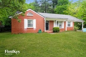 Forest Park house for rent - a small brick house with a green lawn and a black door