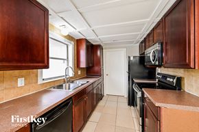 Ocoee house for rent - a kitchen with wood cabinets and black appliances and a sink