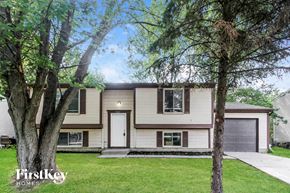 Indianapolis house for rent - A house with a white door and a garage door is surrounded by trees.