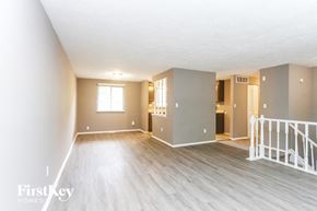 Indianapolis house for rent - A spacious room with wooden floors and white walls, with a staircase leading to another room.