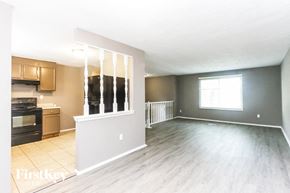 Indianapolis house for rent - A spacious living room with wooden flooring and a window with blinds.