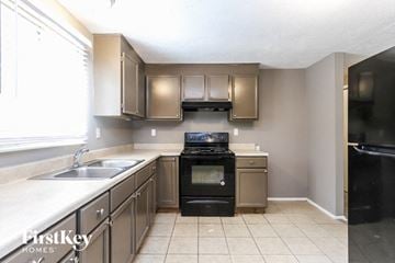 Indianapolis house for rent - A kitchen with a black stove top oven and a black refrigerator.
