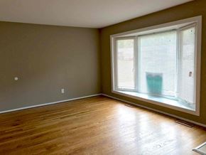 Florissant house for rent - an empty living room with a large window and wood floors