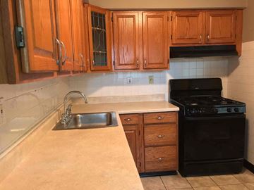 Florissant house for rent - a kitchen with wooden cabinets and a sink and a stove
