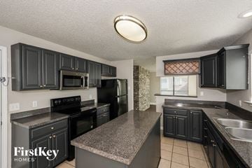 Cedar Hill house for rent - A kitchen with black cabinets and a granite countertop.