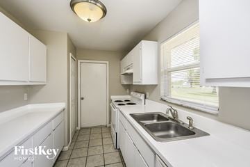 Lehigh Acres house for rent - a kitchen with white cabinets and a sink and a window