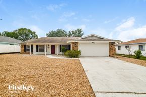 Deltona house for rent - a white house with a driveway and a garage door