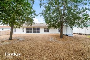 Deltona house for rent - a white house with two trees in the yard
