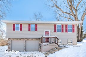 Kansas City house for rent - a yellow house with red shutters and a garage door in the snow