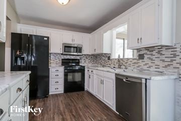Kansas City house for rent - a white kitchen with black appliances and white cabinets