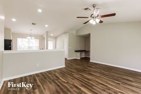 Lehigh Acres house for rent - A spacious room with wooden floors and a ceiling fan.