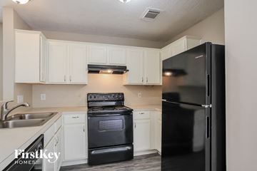 Channelview house for rent - a kitchen with black appliances and white cabinets