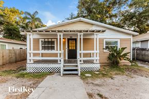 Tampa house for rent - a small tan house with a porch and a black door
