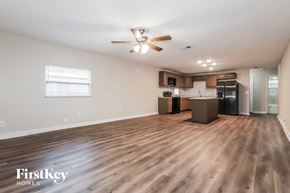 Tampa house for rent - an empty living room with a kitchen and a ceiling fan