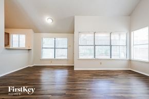 Lewisville house for rent - A spacious room with wooden floors and large windows.