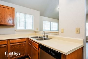 Lewisville house for rent - A kitchen with wooden cabinets and a black dishwasher.