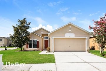 Auburndale house for rent - a beige house with a garage door and a lawn