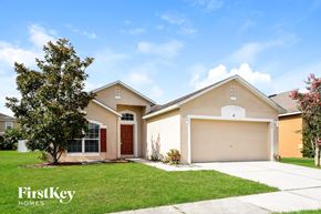 Auburndale house for rent - a beige house with a garage door and a lawn