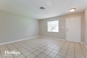 Mount Dora house for rent - an empty living room with a white tile floor and a white door